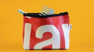 Trousse rouge avec brosse &agrave; dents et peigne sur fond jaune.